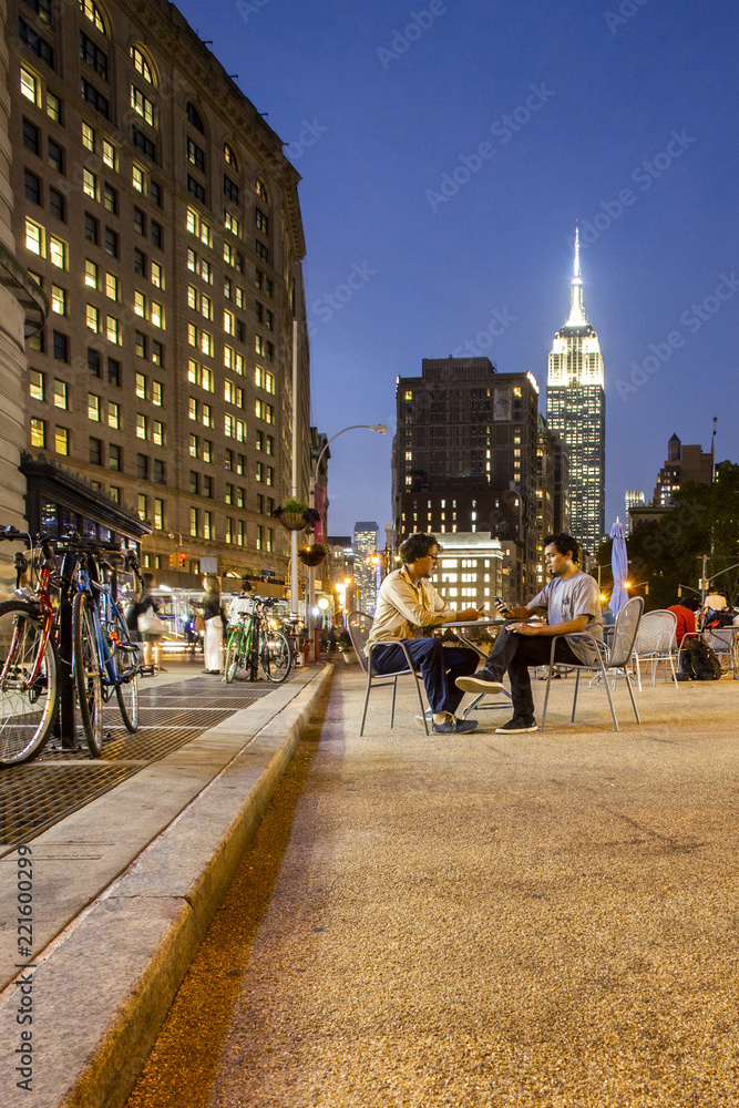 Two men sitting at public table in the Madison Sqaure Park area of New  York, NY with Empire State Building visible in background Stock Photo |  Adobe Stock