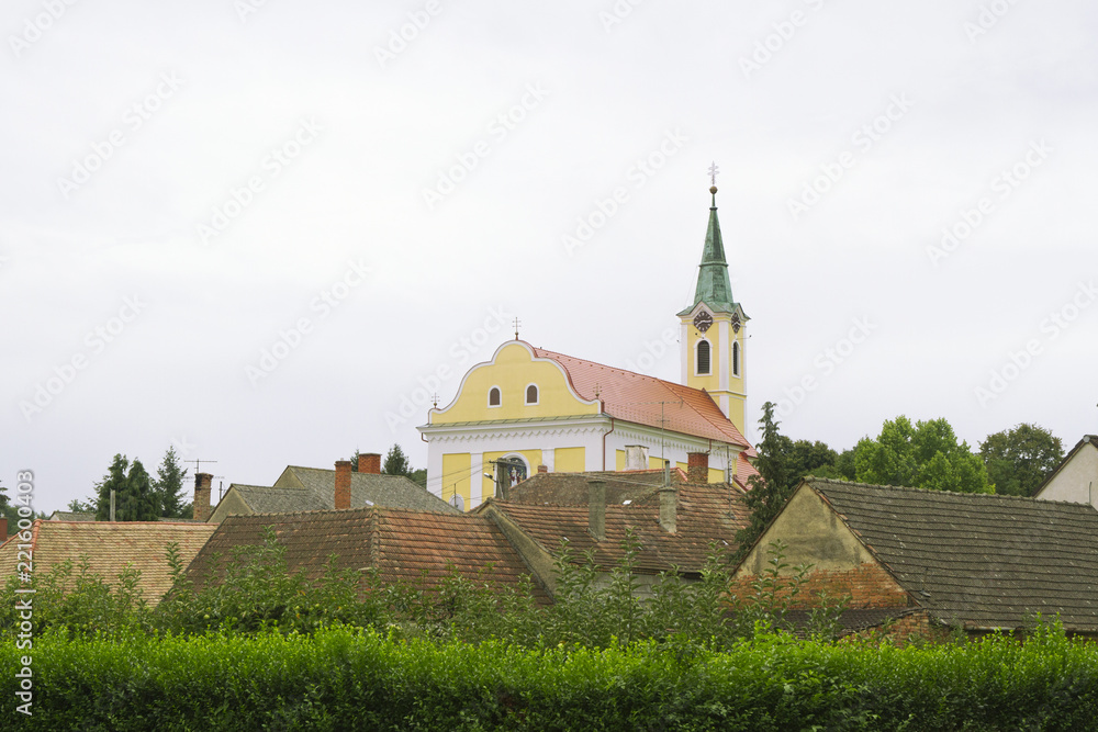 View on the red roofs and yellow church in small Hungarian village. 