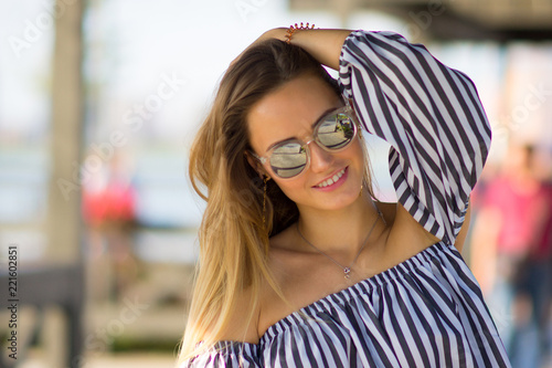 The girl in mirror sunglasses is tidying up on one's side her hair because of the heat. Summer trip concept