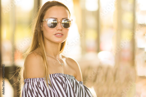Fashionable portrait of a girl in mirror sunglasses in warm tones