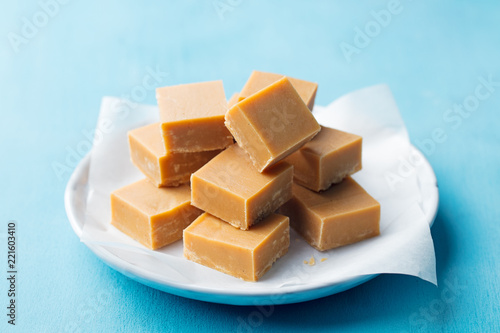 Fresh caramel fudge candies on a plate. Blue background. Close up.