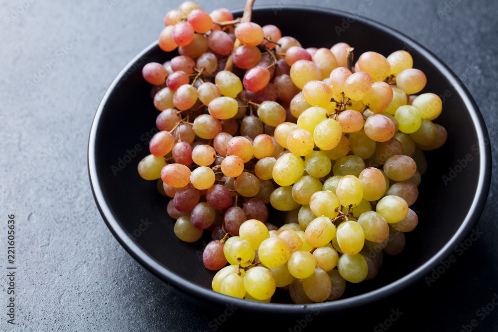 Fresh grape in bowl on a black stone background. Close up. Fresh grape in bowl on a black stone background. Close up.