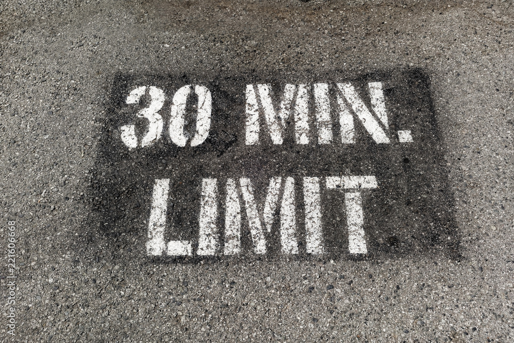 30 MIN. LIMIT parking sign painted on parking lot asphalt. 30 MIN. LIMIT parking sign painted on parking lot asphalt.