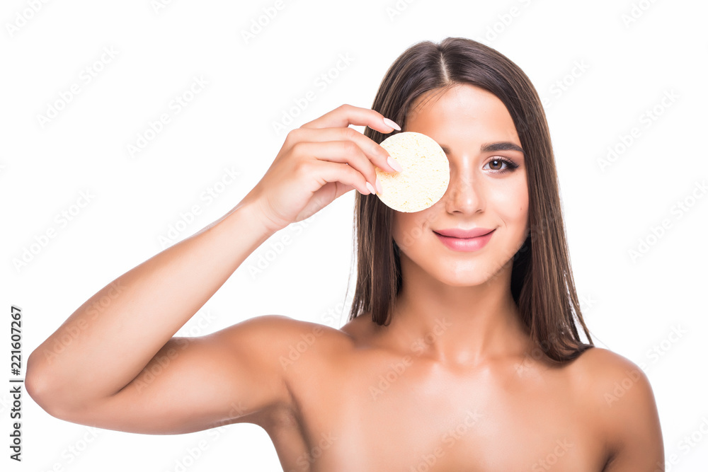 Cute beautiful natural brunette girl cleaning face with cotton sponge smiling looking at camera over white background. Cosmetology and spa. Cute beautiful natural brunette girl cleaning face with cotton sponge smiling looking at camera over white background. Cosmetology and spa.