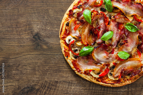 Pizza with Mozzarella cheese, mushrooms, bacon, Tomatoes, pepper, Spices and Fresh Basil. Italian pizza on wooden background.
