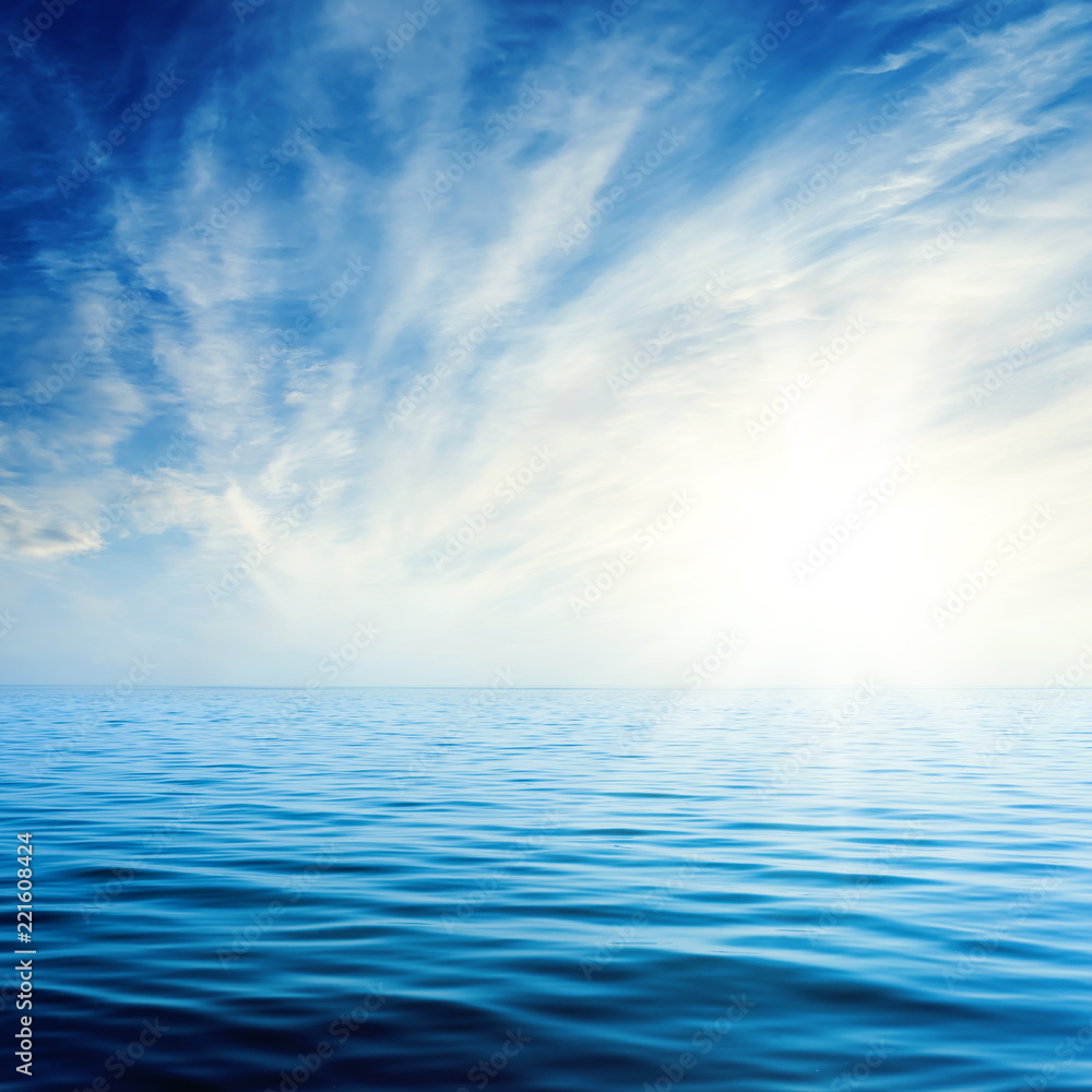 Fototapeta premium sunset in blue sky with clouds over dark sea