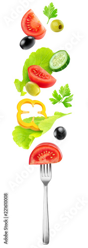Isolated vegetables mix. Fresh salad components (tomato, cucumber, bell pepper, lettuce and olives) flying over a fork isolated on white background with clipping path