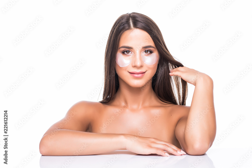 Close up portrait of attractive girl with naked shoulders using, having, applying patches under close eyes, fight with dark circles, standing over white background. Wellbeing concept Close up portrait of attractive girl with naked shoulders using, having, applying patches under close eyes, fight with dark circles, standing over white background. Wellbeing concept