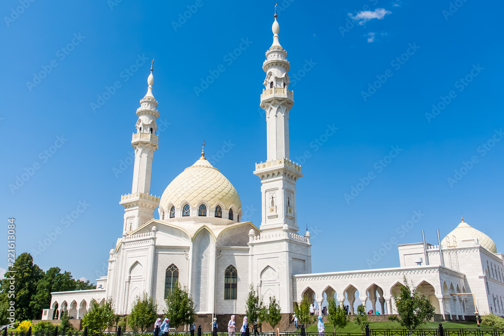 Large white mosque on blue sky background.