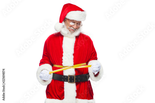 Christmas. Santa Claus is measuring waist with a tape. The concept of weight loss, healthy eating. Isolated on white background.