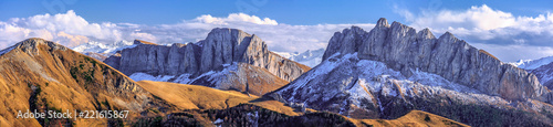 Beautiful scenic autumn landscape of majestic Acheshbok rocky mountain peaks called Devil's Gate covered with snow under blue sky with clouds. Wide panoramic mountain scenery in West Caucasus, Russia