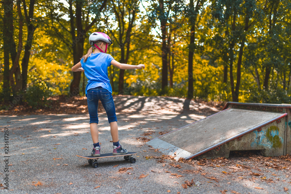 Obraz premium Ein Mädchen skatet mit dem Longboard auf einem Skatepark auf eine Rampe zu