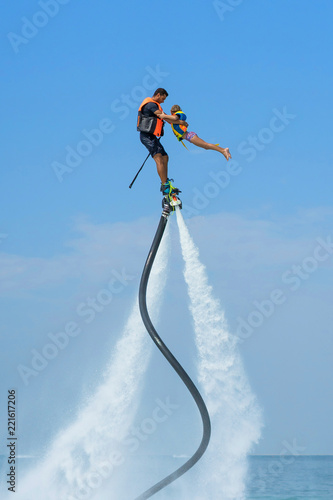 Father and his daughter posing at new flyboard at Caribbean tropical beach. Positive human emotions, feelings, joy. Funny cute child making vacations and enjoying summer.