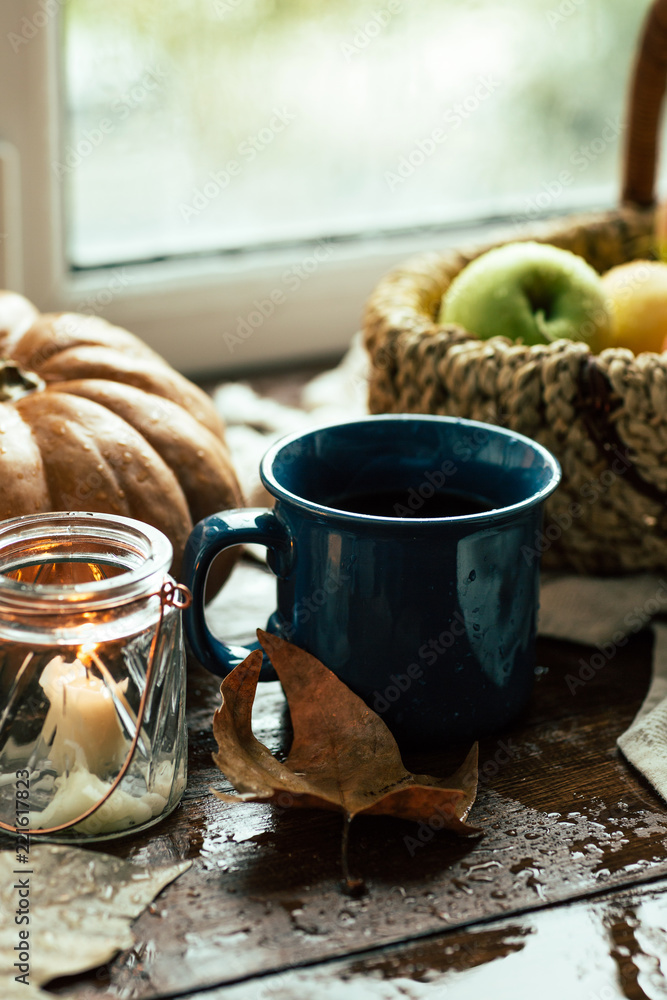 Autumn, window, tea mug and raindrops, fallen leaves, coziness, apples in a basket and pumpkin