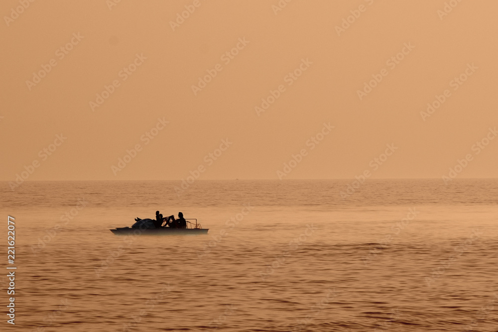 Romantic silhouette of a pedal boat on the sea in the evening/sunset. It can be used as a wallpaper.