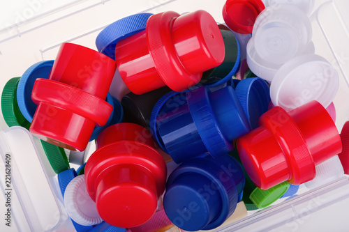 Colorful plastic lids in a box on white background.