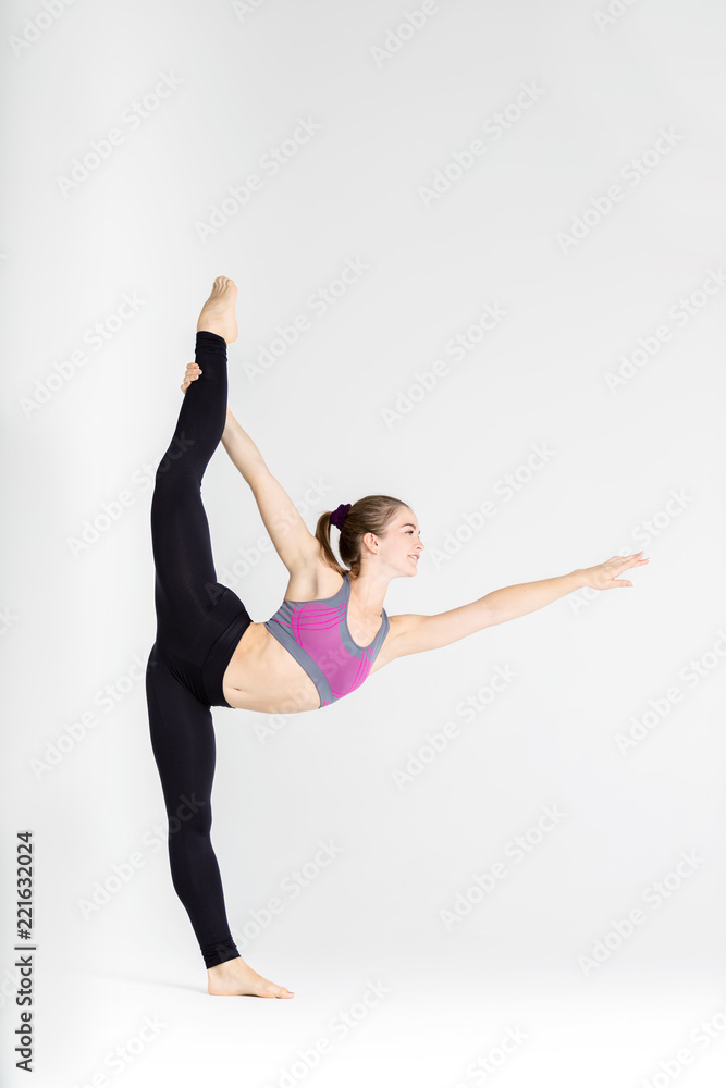 Fototapeta premium Young sportwoman stretching muscles on white background