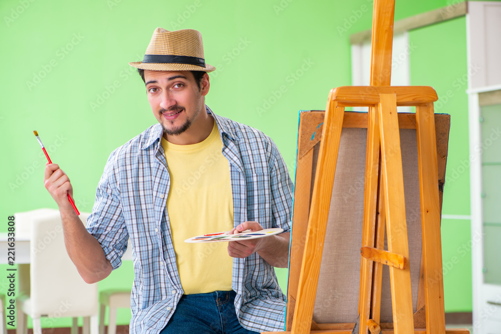 Young male artist working on new painting in his studio Young male artist working on new painting in his studio