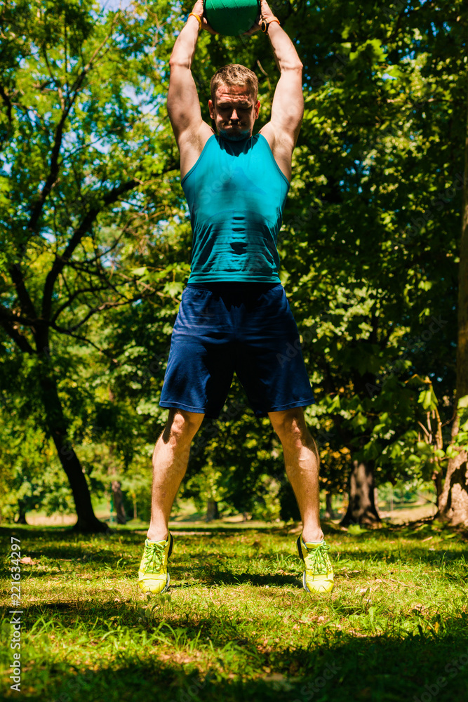 Athletic guy doing workout with medecine ball in the park Athletic guy doing workout with medecine ball in the park