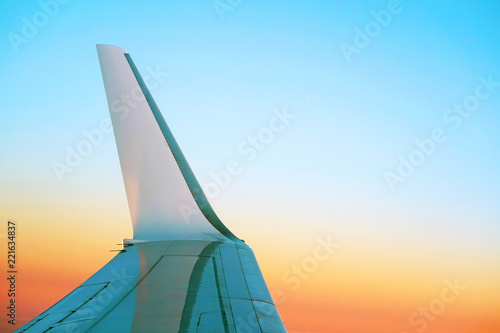 The wing of an airplane flying in the morning sky. The wing of the plane with the rising of the sun in a light torch.