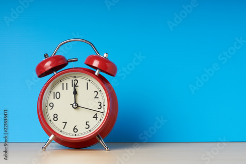 Red alarm clock on blue background with copy space.