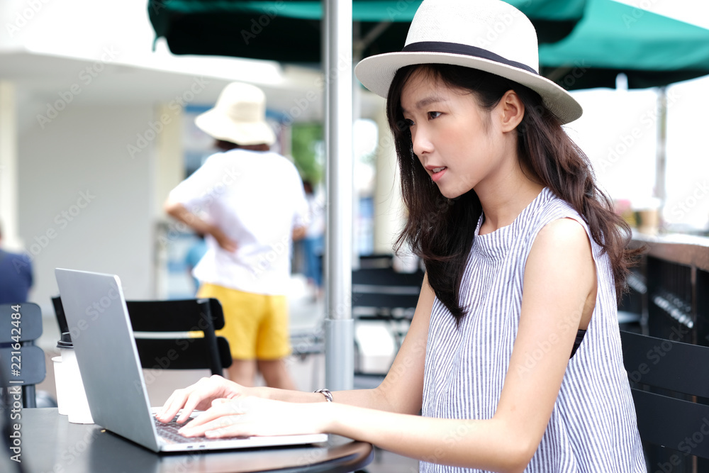 Young asian woman using laptop computer sitting at cafe city outdoors, working outdoors, people and technology, lifestyles, education, business concept