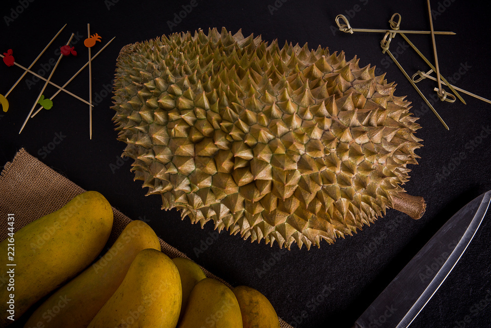 Durian on mango sackcloth with knife, Black stone background Durian on mango sackcloth with knife, Black stone background