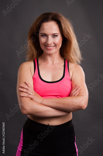 Beautiful, athletic, slender woman in a pink T-shirt and black shorts on a dark background © queen1987