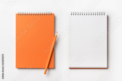 Top view of orange spiral notebook and pencil