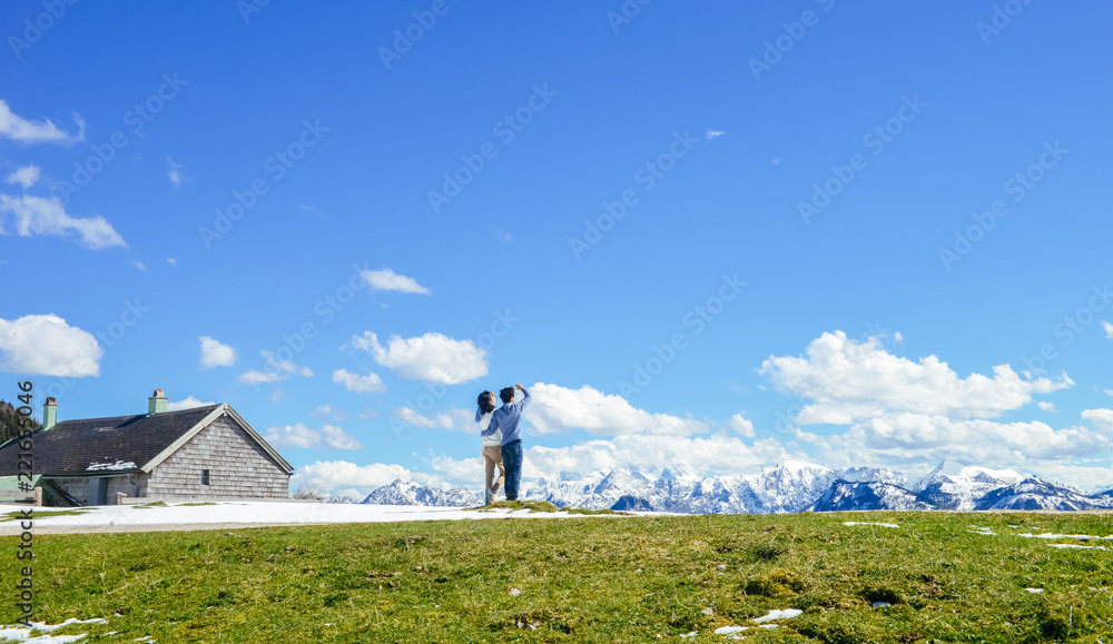 Obraz premium Young Asian couple stand at edge of Schafberg mountain (the mountain in movie 'sound of music'), Austria, looking far away