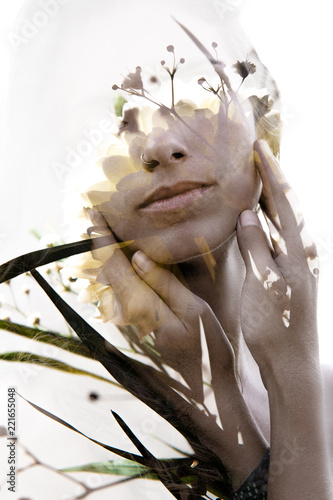 Double exposure portrait of a young girl softly touching her face combined with delicate yellow and white flower petals