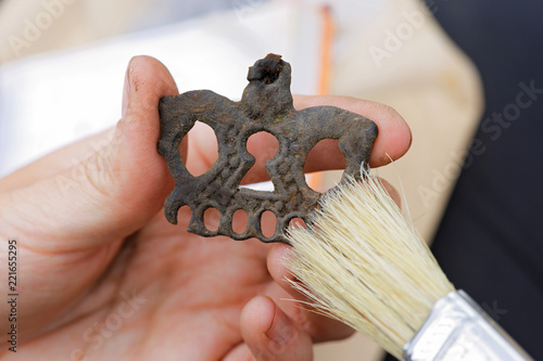 Obraz na plátně An archaeologist cleans a medieval bronze pendant in the animal style