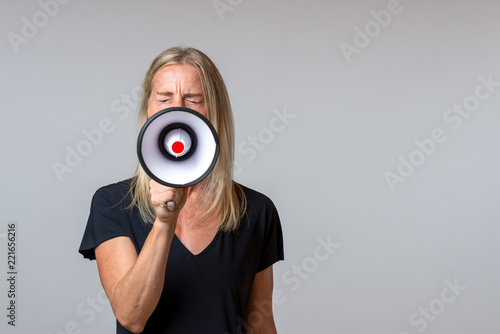 Angry woman yelling into a handheld megaphone photo