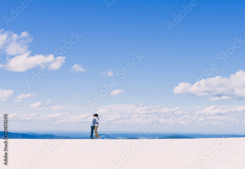 年轻亚裔情侣在雪山边缘互相拥抱,夏夫山 (电影《音乐之声》拍摄地),奥地利,
