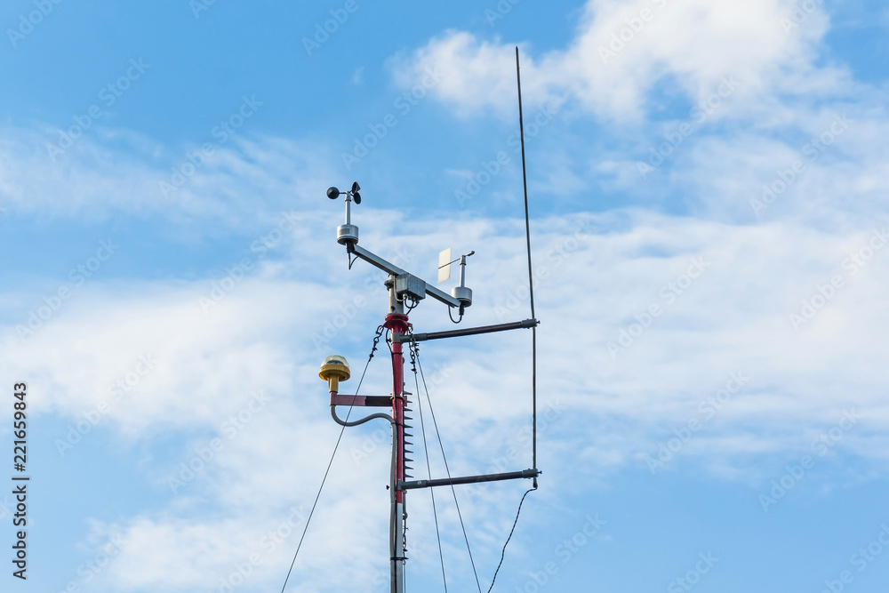 Automatic weather station, with a weather monitoring system. Against the background of a blue sky with clouds. Automatic weather station, with a weather monitoring system. Against the background of a blue sky with clouds.