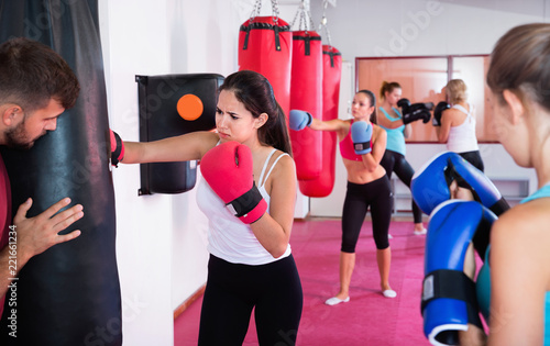 Sporty girl is boxing near punching bag in gym. © JackF