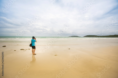 Photographer from behind the sea beach.Photographer taking photos on the tropical beach.young man take photo of island beach and sea,seascape background for summer holiday and vacation travel concepts