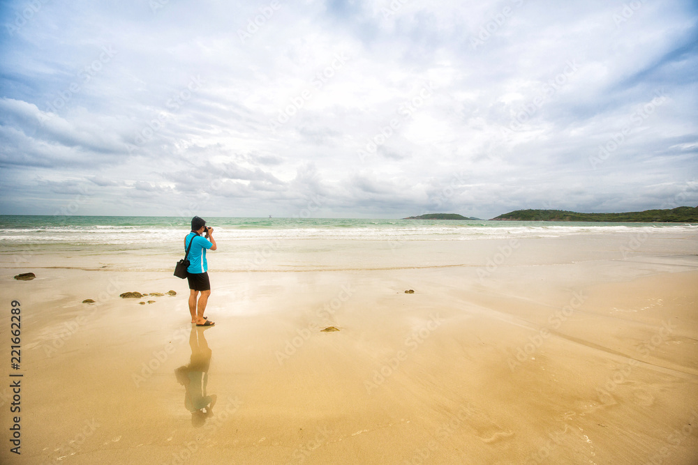 Photographer from behind the sea beach.Photographer taking photos on the tropical beach.young man take photo of island beach and sea,seascape background for summer holiday and vacation travel concepts Photographer from behind the sea beach.Photographer taking photos on the tropical beach.young man take photo of island beach and sea,seascape background for summer holiday and vacation travel concepts