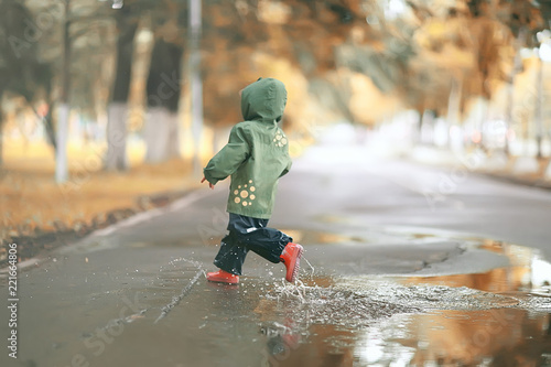 Fototapeta Naklejka Na Ścianę i Meble -  girl runs around the puddles in the autumn park, childhood game