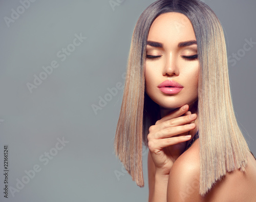 Fashion hairstyle. Ombre dyed hair. Beauty Model girl with perfect healthy hair and beautiful makeup posing in studio, young woman portrait on grey background