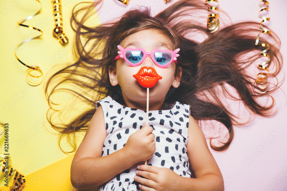 Obraz premium Cute little girl in funny glasses with plastic masquerade lips on stick.