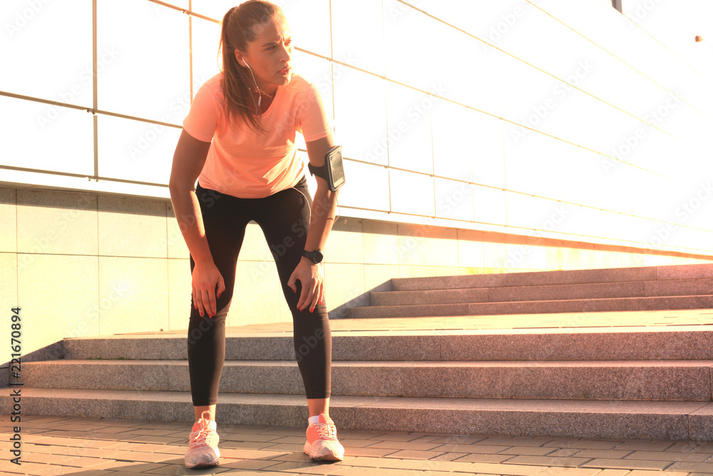 Young fitness attractive sporty girl resting after intensive evening run outdoor at sunset in city. Young fitness attractive sporty girl resting after intensive evening run outdoor at sunset in city.