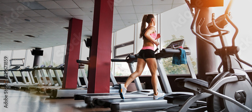 slim beautiful sporty woman running at the treadmill in the gym. Concept of cardio exercises and healthy way of life