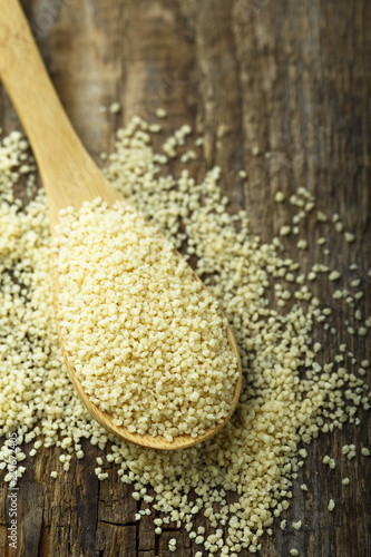 Dry couscous grain in the wooden spoon