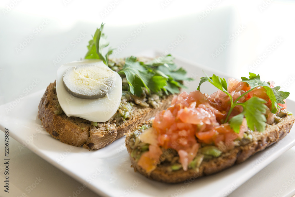 2, two sandwiches with avocado and tomato and boiled egg on a plate, chopped avocado and tomatoes on bread pieces 2, two sandwiches with avocado and tomato and boiled egg on a plate, chopped avocado and tomatoes on bread pieces
