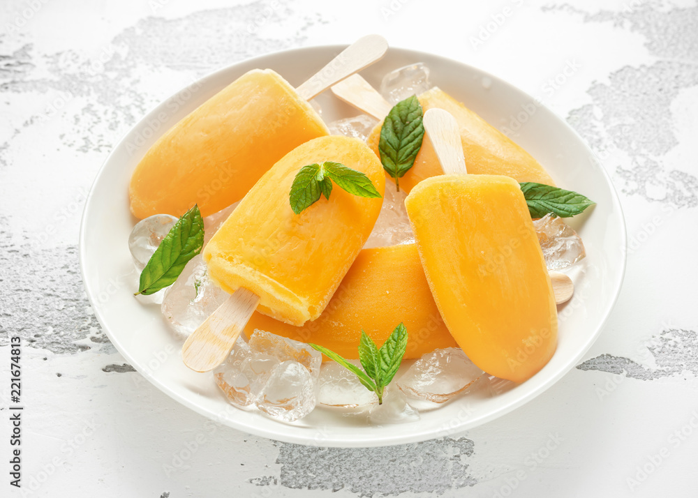 Popsicles, ice lollies on stick with sweet orange juice in white plate with ice Popsicles, ice lollies on stick with sweet orange juice in white plate with ice