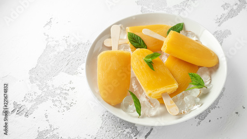 Popsicles  ice lollies on stick with sweet orange juice in white plate with ice