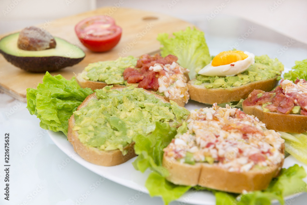 sandwiches with avocado, egg and tomato on lettuce leaves on a plate, breakfast,  a healthy snack