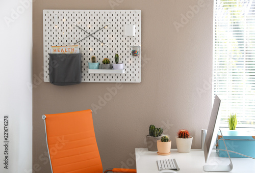 Modern workplace and pegboard with different cacti in room photo