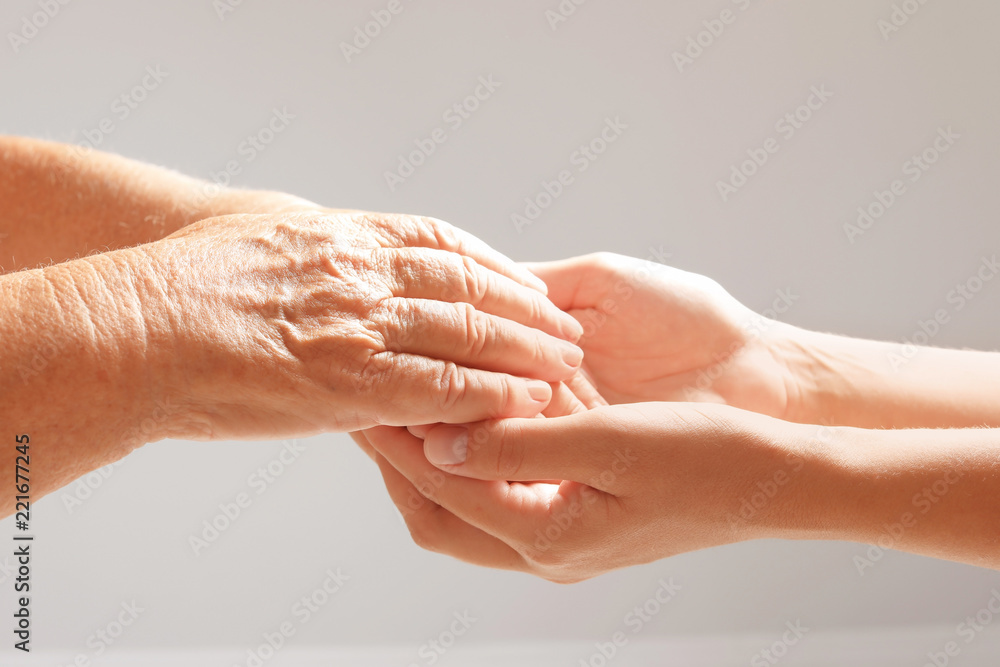 Helping hands on grey background, closeup. Elderly care concept Helping hands on grey background, closeup. Elderly care concept